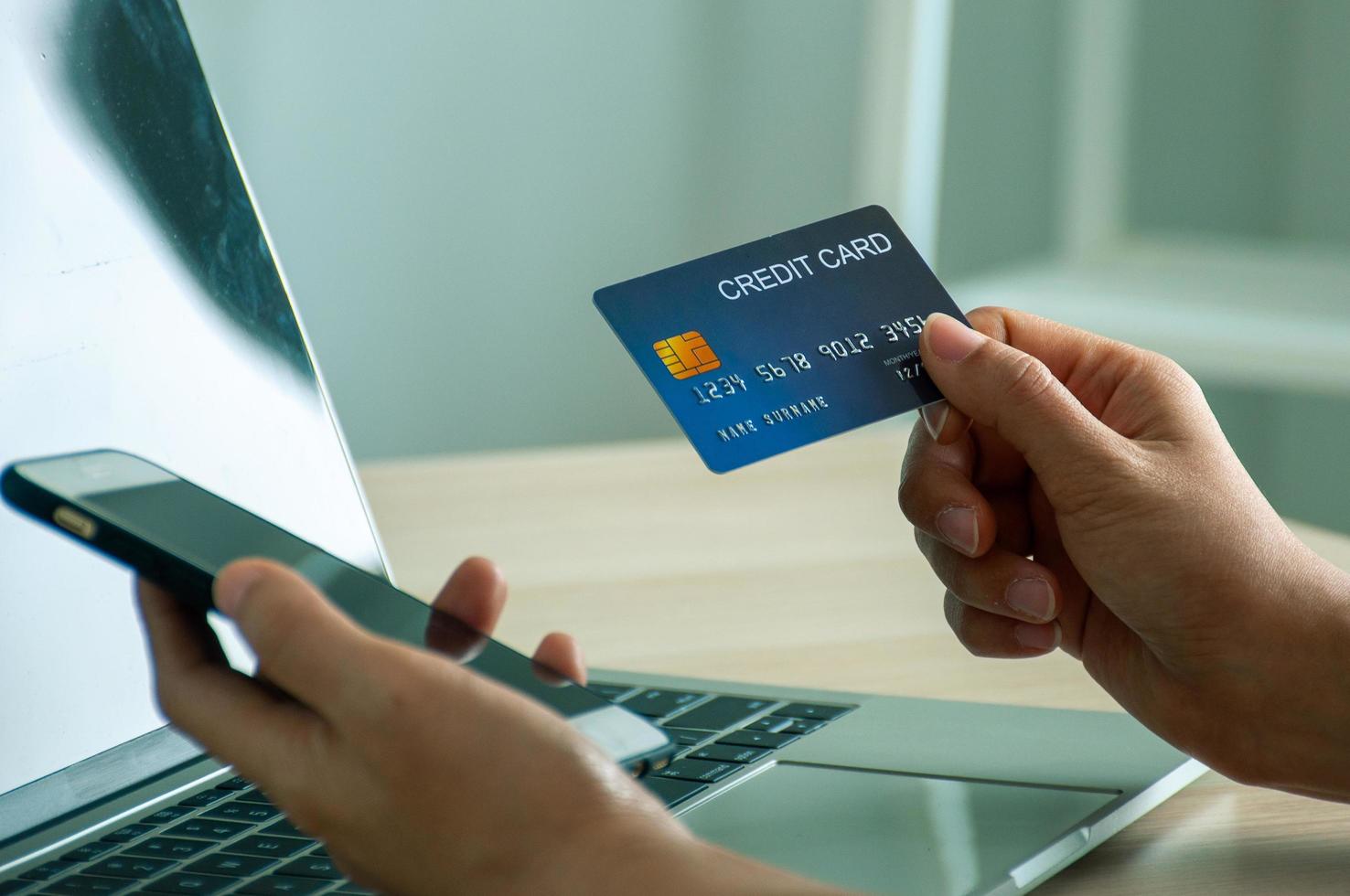 une jeune femme utilise une carte de crédit pour effectuer des achats en ligne sur une application ou un site Web pour ordinateur portable. concept de commerce électronique et de magasinage en ligne. photo