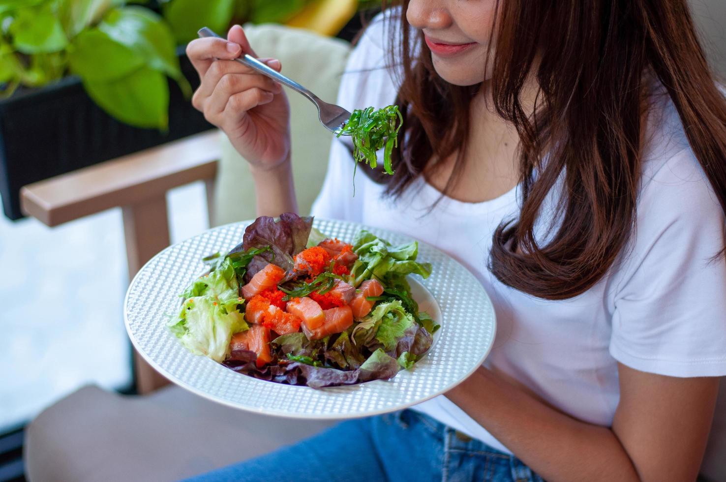 les jeunes femmes ayant l'intention de perdre du poids mangent une salade de légumes au saumon pour une bonne santé. femmes choisissant un concept de régime alimentaire sain photo
