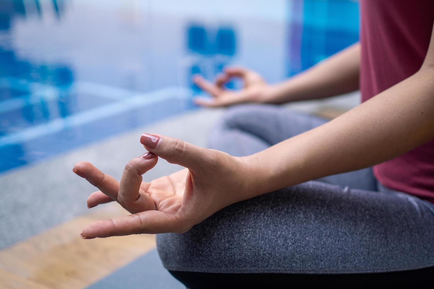 les jeunes femmes portent des combinaisons de sport modernes, méditent, font du yoga, des postures relaxantes, s'installent confortablement au bord de la piscine. l'exercice à la maison et dans les espaces privés. concept de mode de vie sain photo