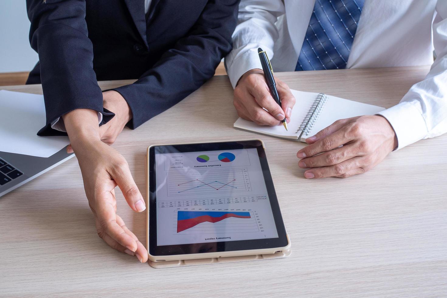 les hommes d'affaires et les consultants parlent de tableaux et de graphiques qui montrent les résultats du travail pendant les pertes et les bénéfices réduits. suggérer les méthodes de travail les plus efficaces. photo