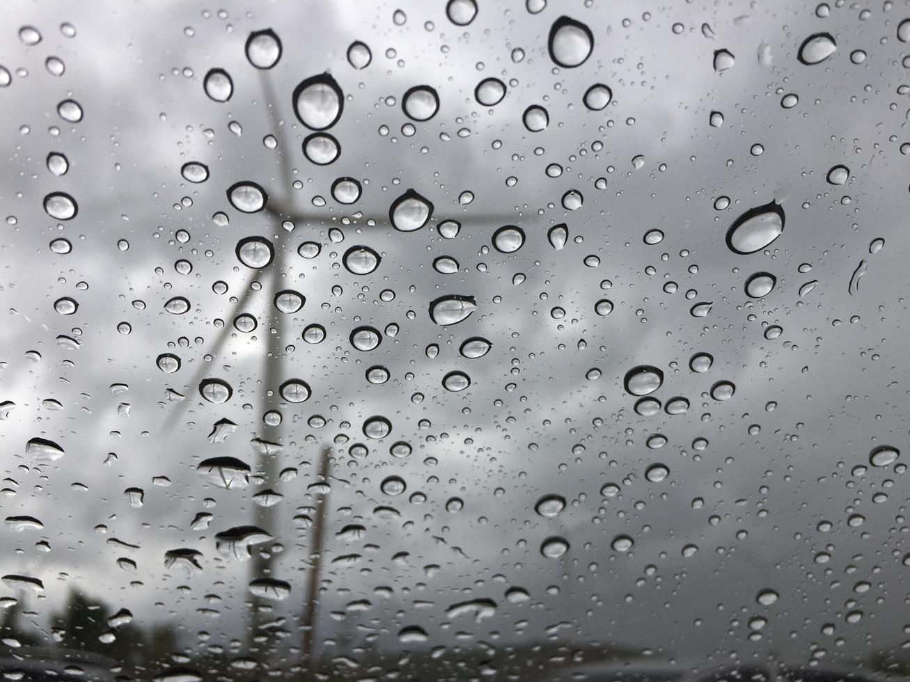 la pluie sur la vitre de la voiture à l'extérieur est une vue sur le moulin à vent. fond triste et solitaire photo