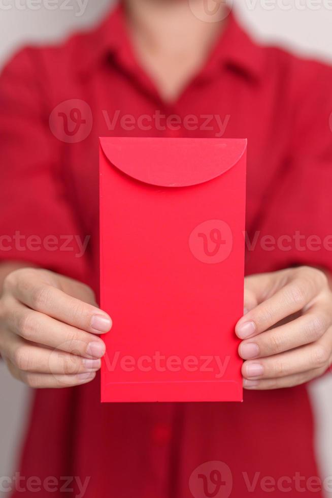 femme tenant une enveloppe rouge chinoise, cadeau en argent pour les vacances du nouvel an lunaire photo