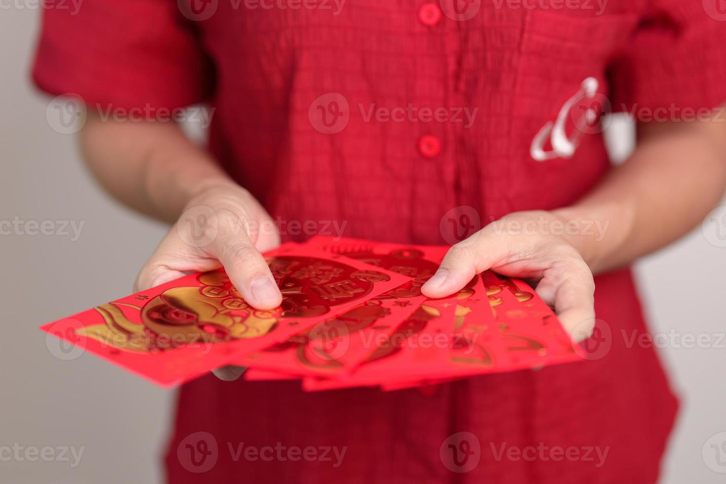 femme tenant une enveloppe rouge chinoise avec lapin doré et mot de bénédiction, cadeau en argent pour les vacances du nouvel an lunaire. phrase chinoise signifie bonheur, en bonne santé, chanceux et riche photo