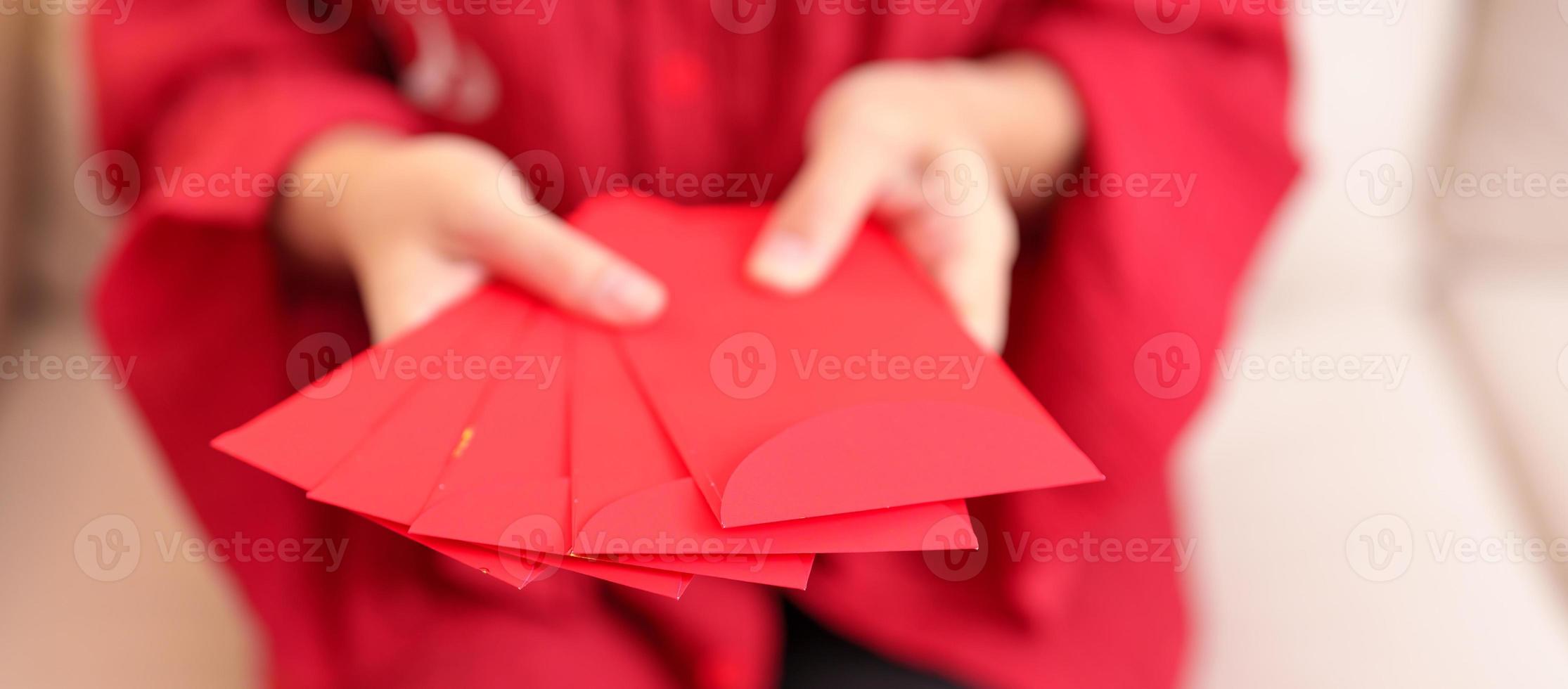 femme tenant une enveloppe rouge chinoise, cadeau en argent pour les vacances du nouvel an lunaire photo