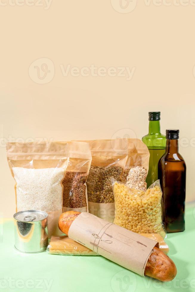 stock de produits alimentaires dans des emballages en papier et cellophane sur beige-vert. céréales, pâtes, bouteilles d'huile, boîte de conserve, pain. photo