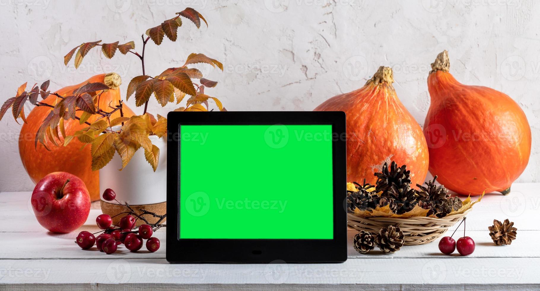 citrouilles, feuilles d'automne, cônes et cadre photo électronique avec écran vert sur fond clair. bannière.