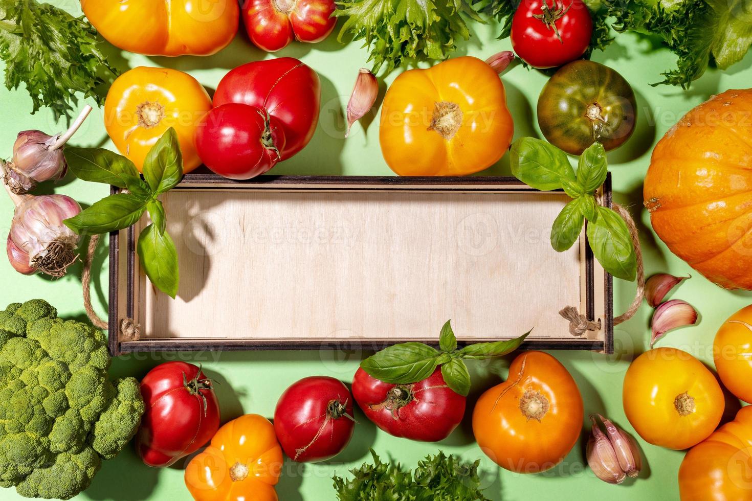 vue de dessus récolte de légumes frais de la ferme sur fond vert pastel avec maquette sur une petite boîte en bois vide. photo