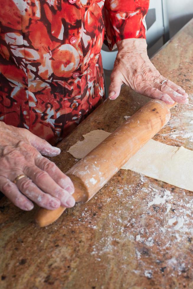 dessert de Noël typique des Asturies. mains de femme âgée avec un rouleau à pâtisserie se préparant avec de la pâte casadielles. gastronomie traditionnelle photo