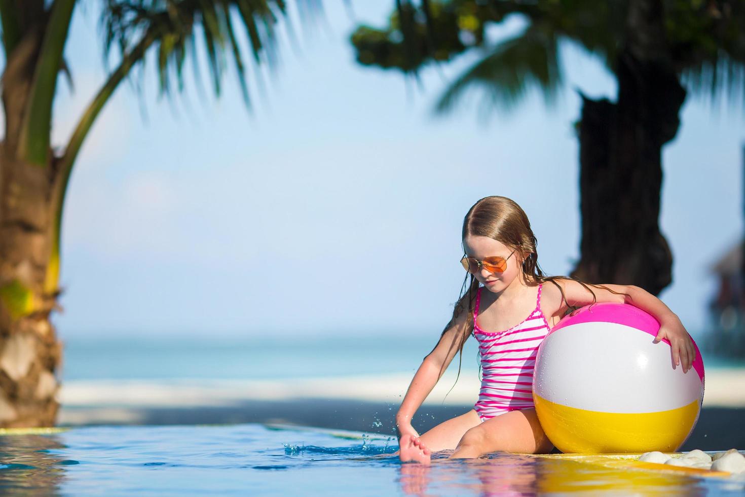fille avec un ballon de plage à la piscine photo