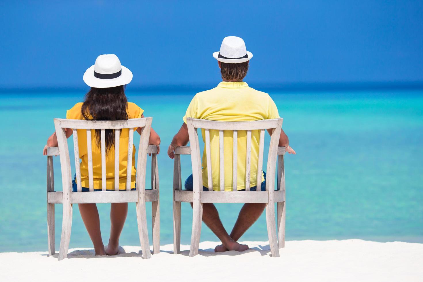 couple assis sur des chaises blanches sur une plage photo