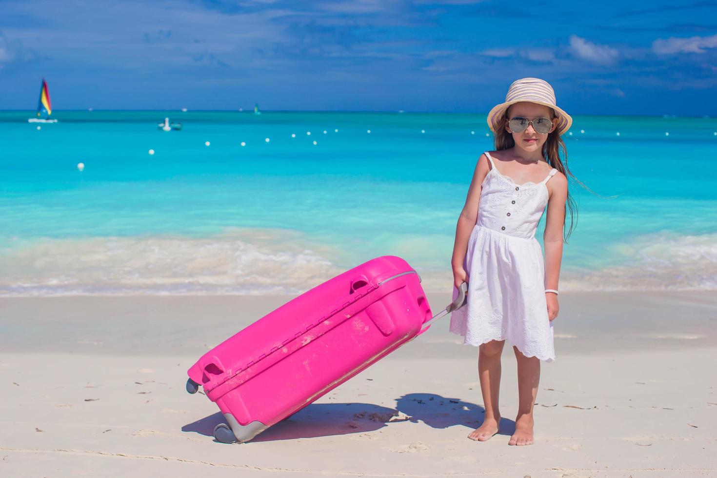 fille avec une valise rose sur une plage blanche photo