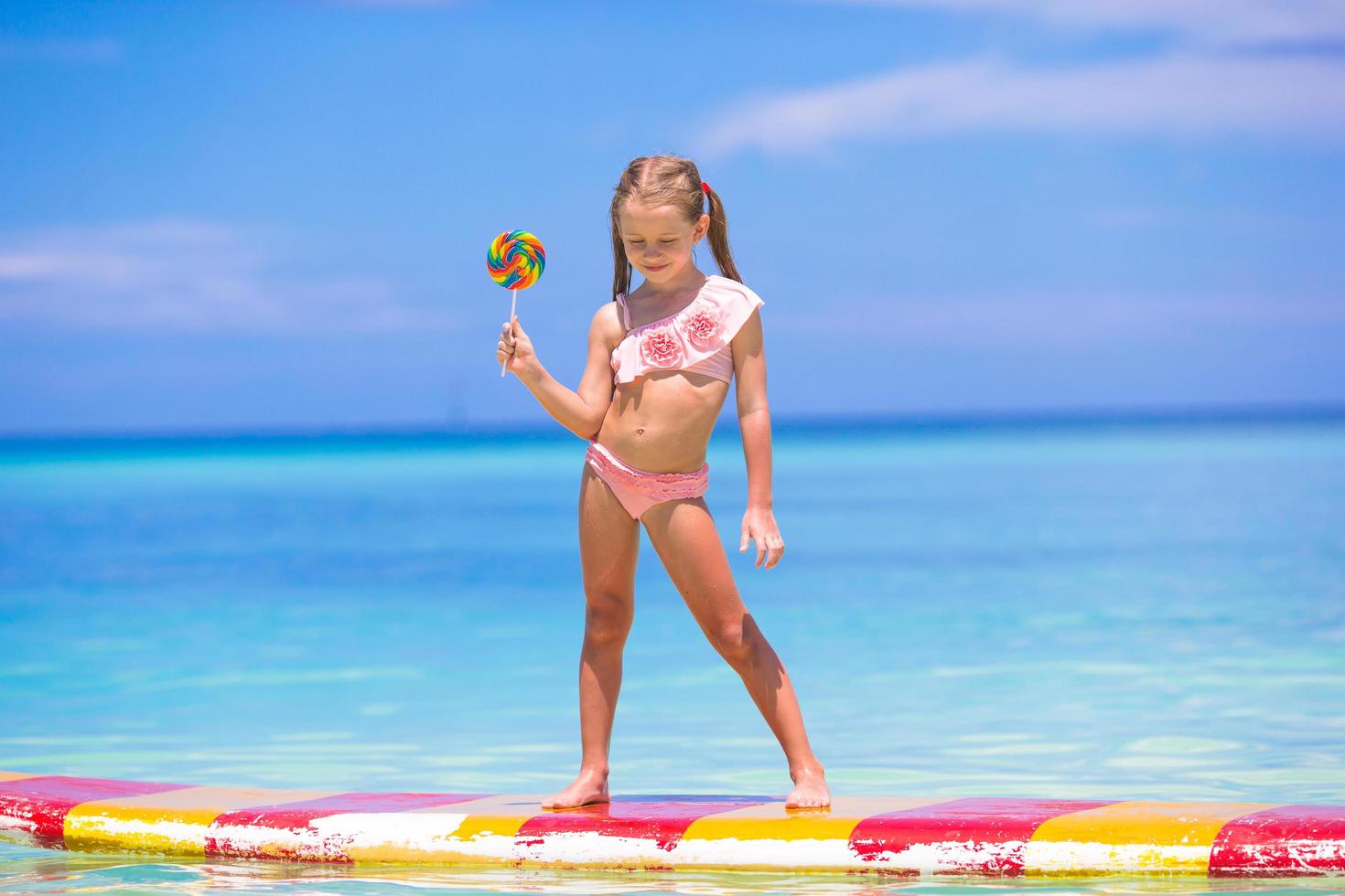 fille tenant une sucette sur une planche de surf photo