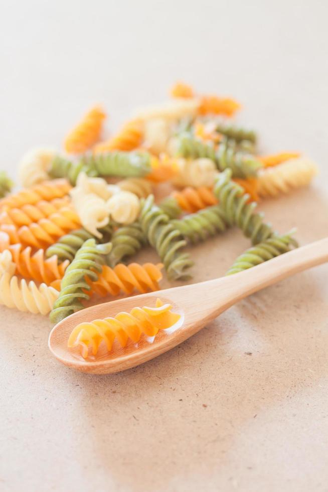 pâtes fusilli crues avec une cuillère en bois photo