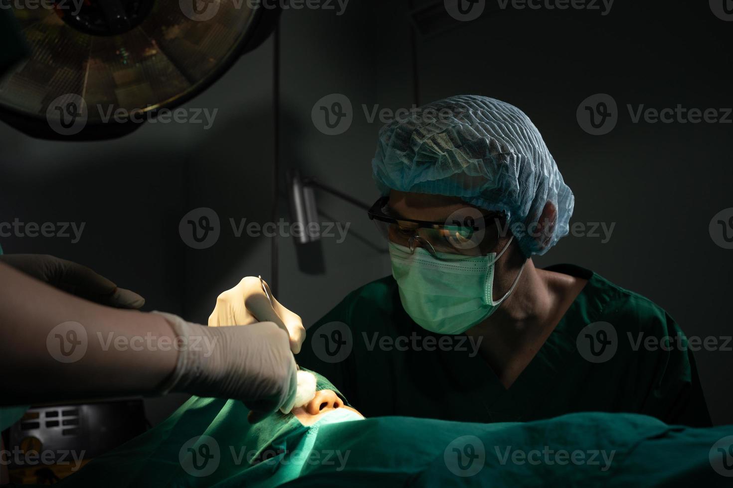 équipe de chirurgiens professionnels asiatiques effectuant une intervention chirurgicale dans la salle d'opération, chirurgien, assistants et infirmières effectuant une intervention chirurgicale sur un patient, un concept de traitement du cancer et des maladies des soins de santé photo
