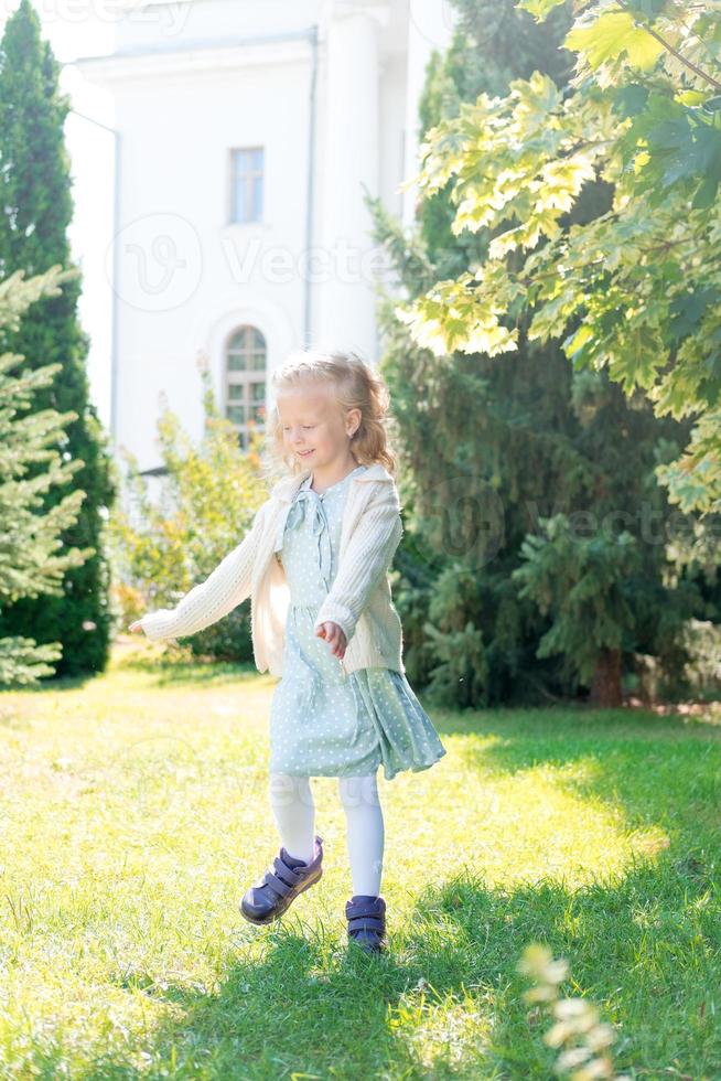 enfant tourbillonnant, dansant joue sur le pré. petite fille aux cheveux blonds tourbillonne au soleil. fille aux cheveux bouclés aime la vie. enfance heureuse. photo