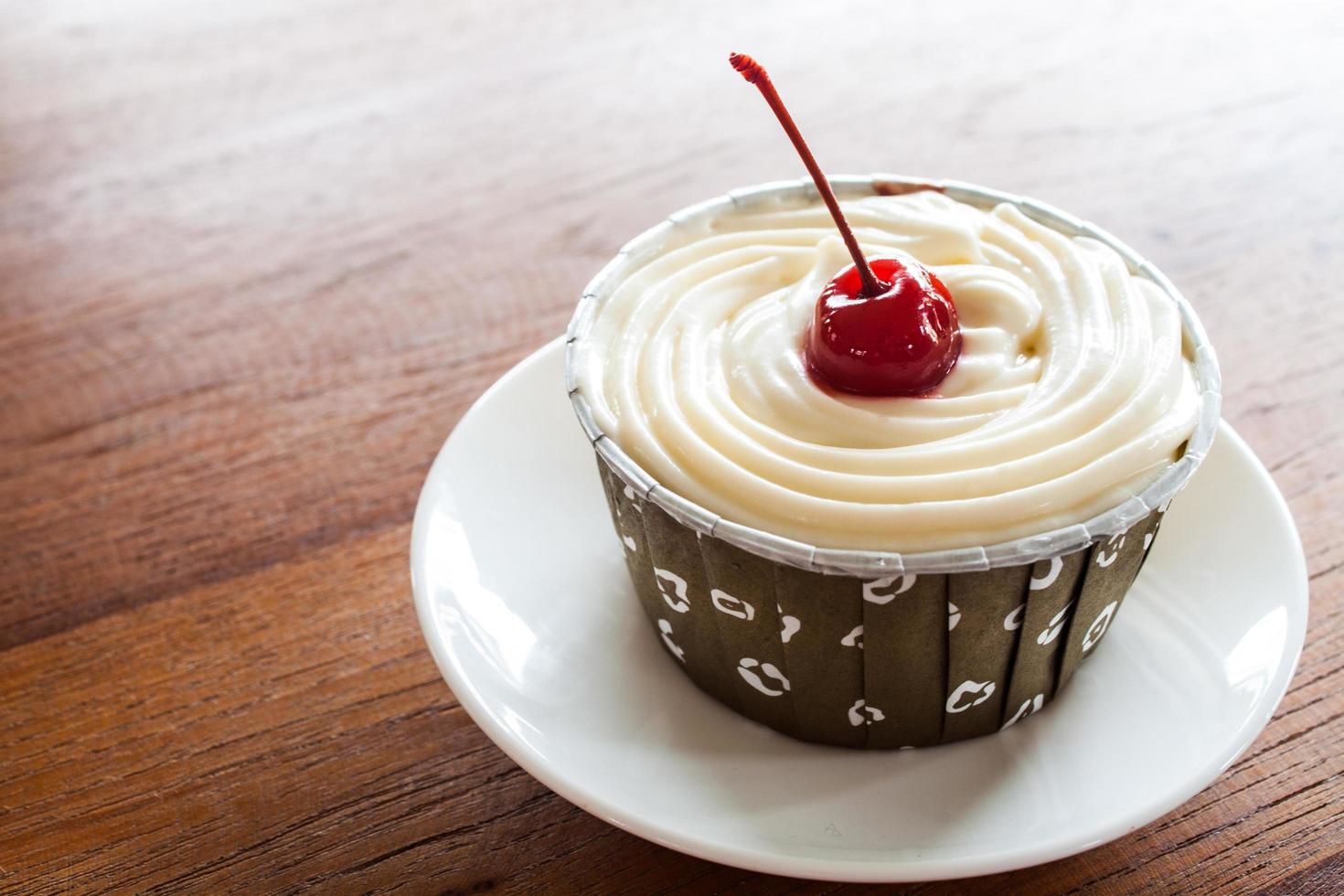 Cupcake avec cerise rouge sur une plaque blanche photo