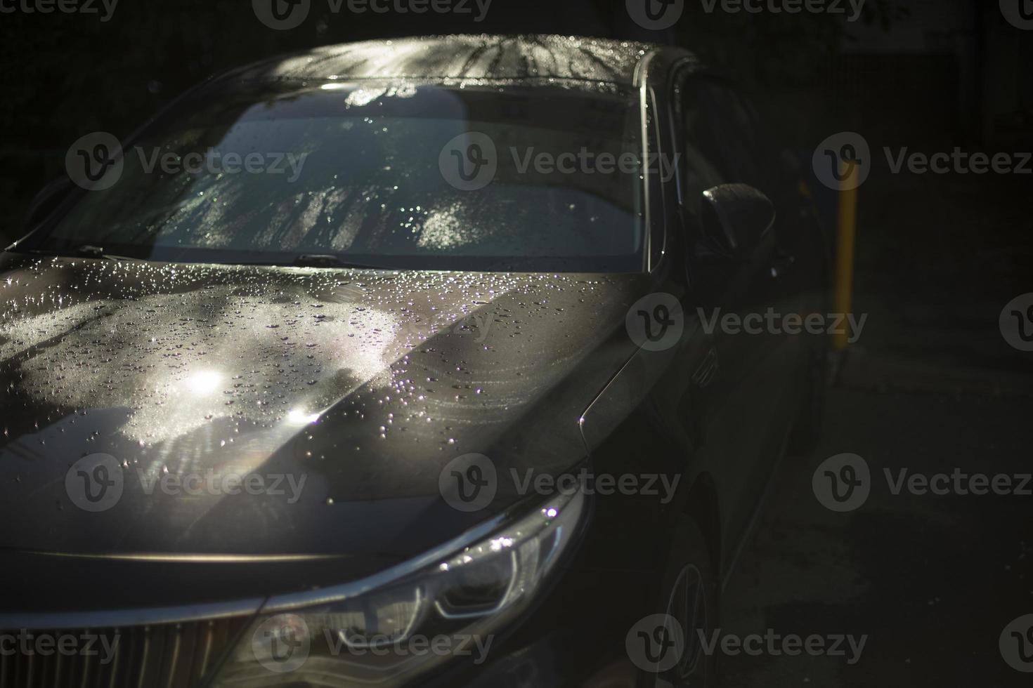 voiture dans le parking. voiture noire au soleil. la voiture est en gouttes. photo