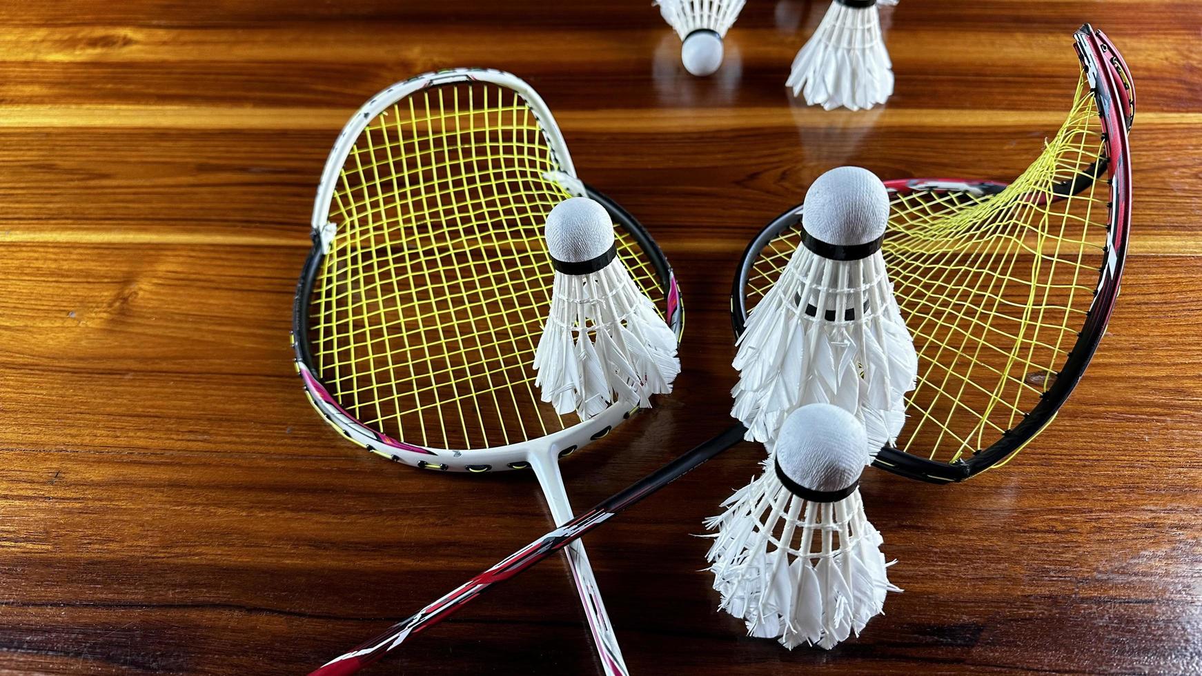 gros plan de raquettes de badminton cassées et de coqs de navette de badminton blancs sur fond de bois marron photo