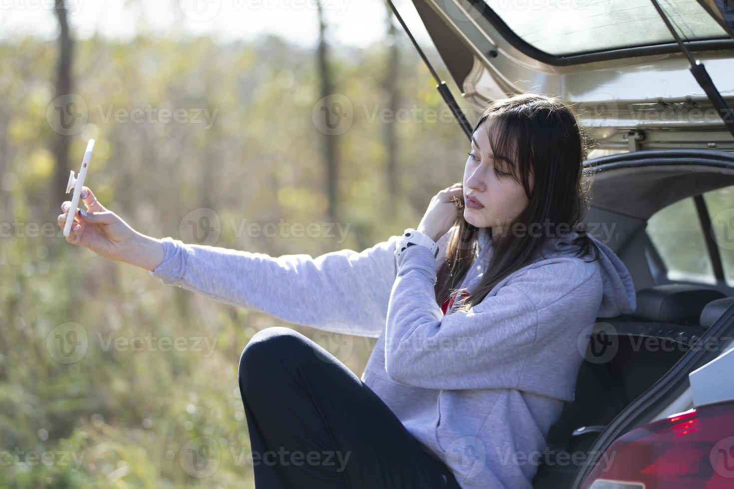 portrait d'une belle fille à l'extérieur qui utilise un smartphone, partage du contenu numérique entre elles et aime prendre une photo de selfie.