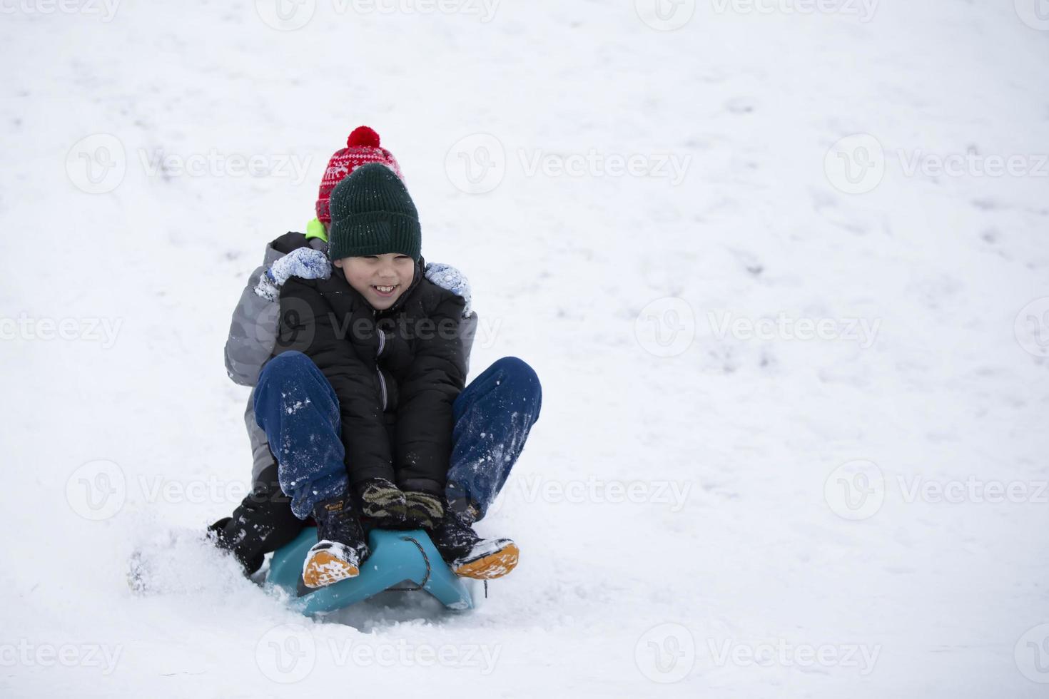 enfants en hiver. les amis garçons font de la luge. photo