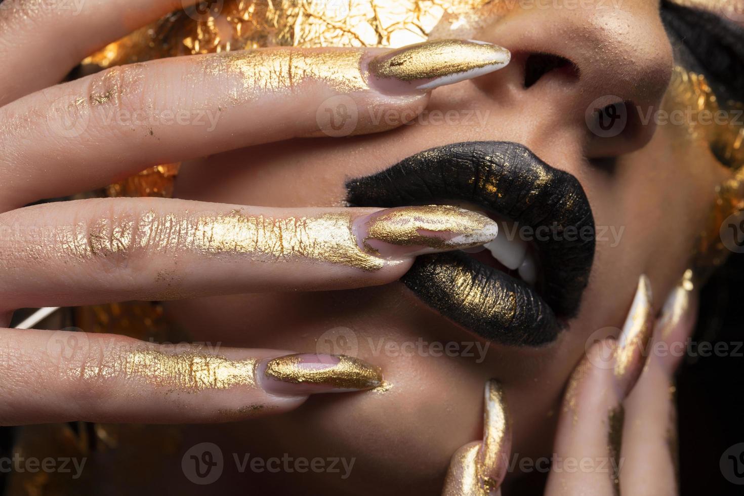 beauté mannequin fille avec maquillage doré et corps sur fond noir. art corporel doré. le visage doré d'une belle dame est touchant. portrait artistique. photo