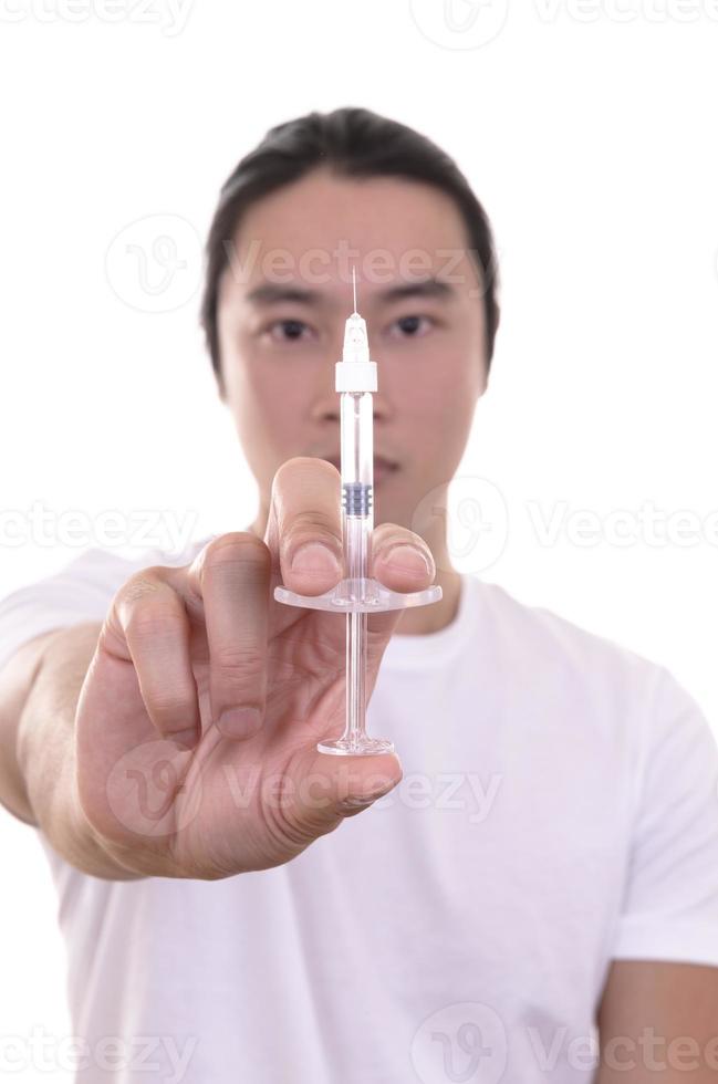 jeune homme asiatique tenant une injection de remplissage devant son visage. homme asiatique dans un salon de beauté. clinique de chirurgie plastique. photo