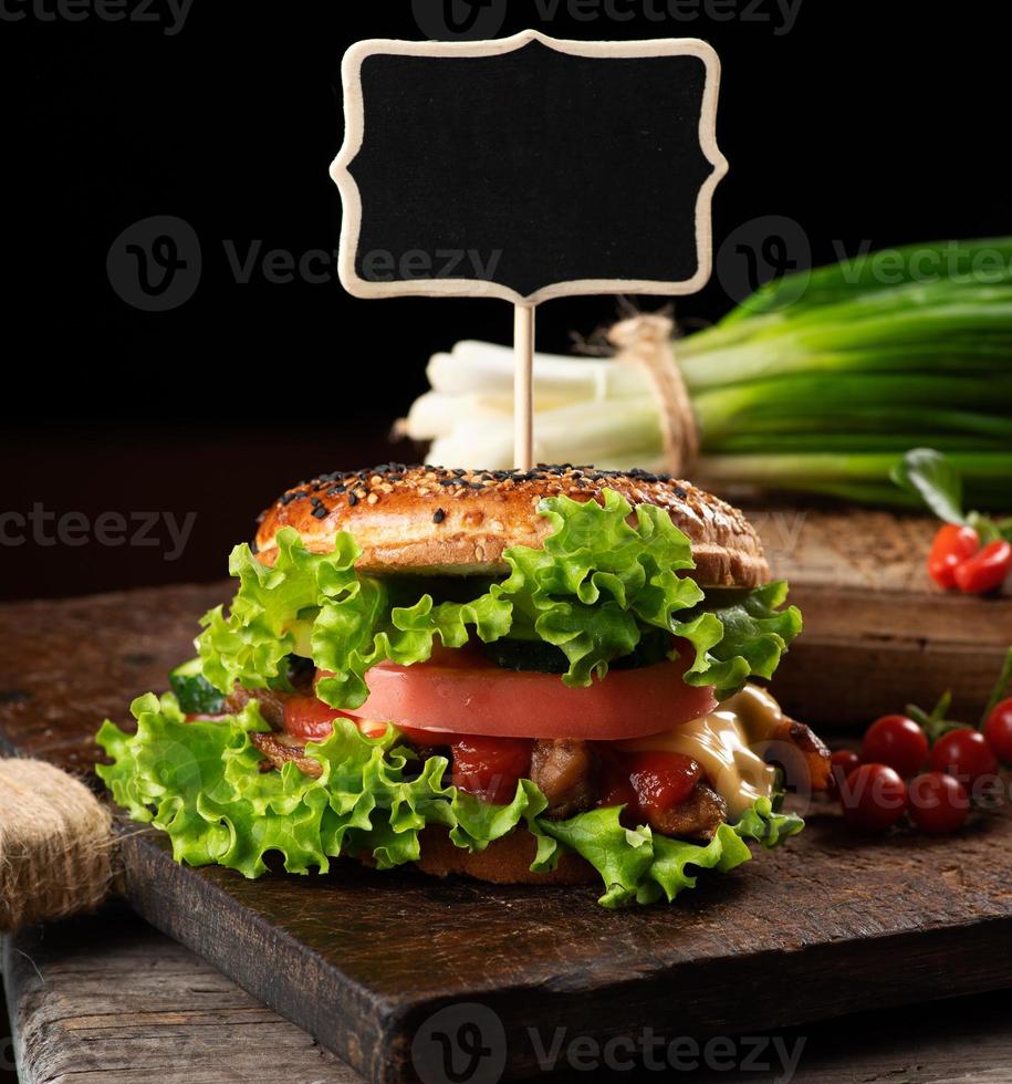 cheeseburger avec viande hachée, laitue verte et ketchup sur une planche de cuisine marron en bois photo