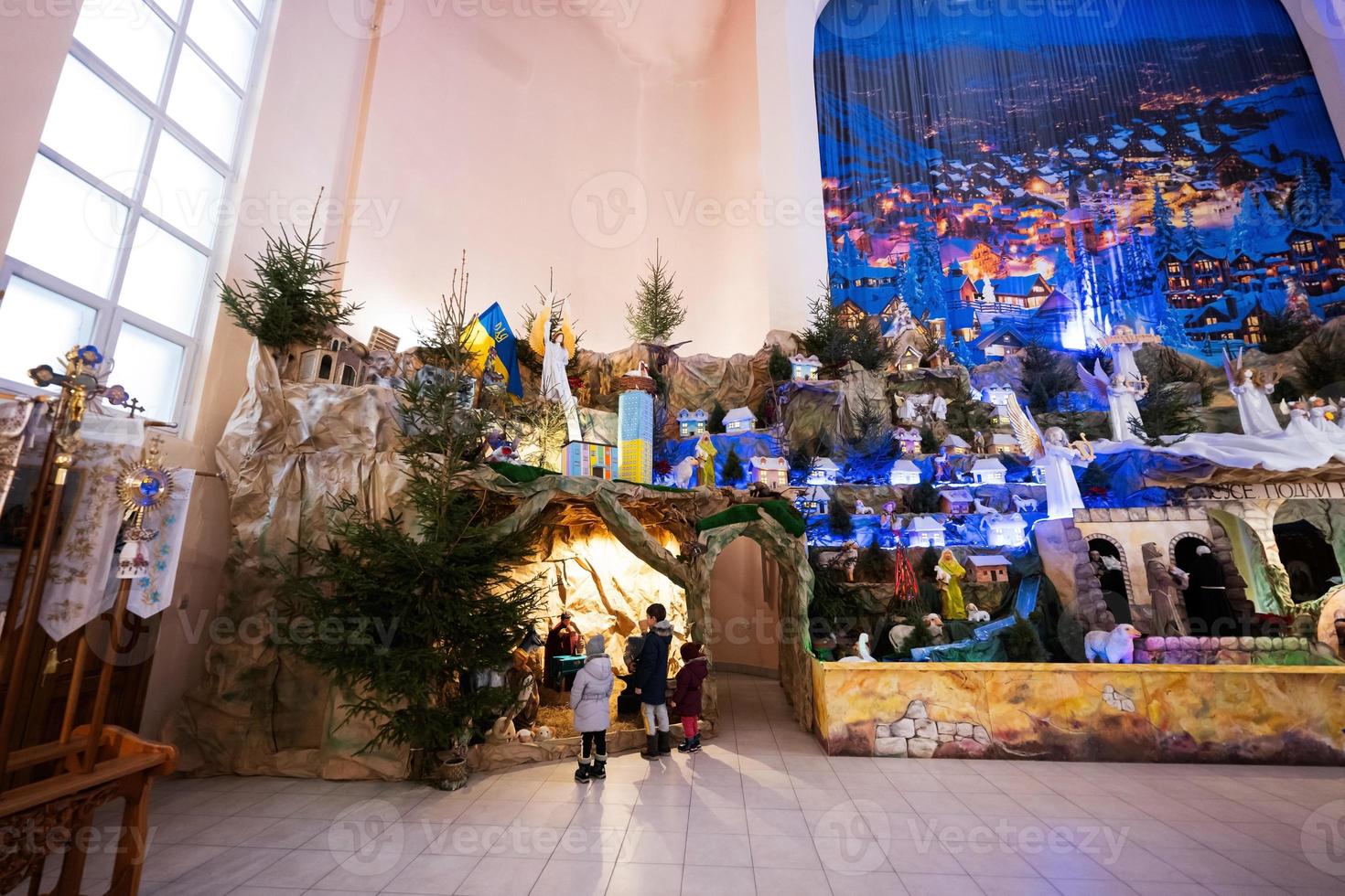 dos de trois enfants regardant dans la crèche de noël à l'église. photo