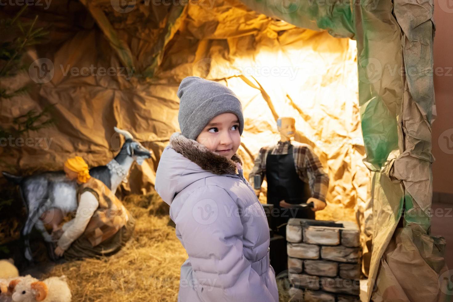 fille regarde la crèche de noël à l'église. photo