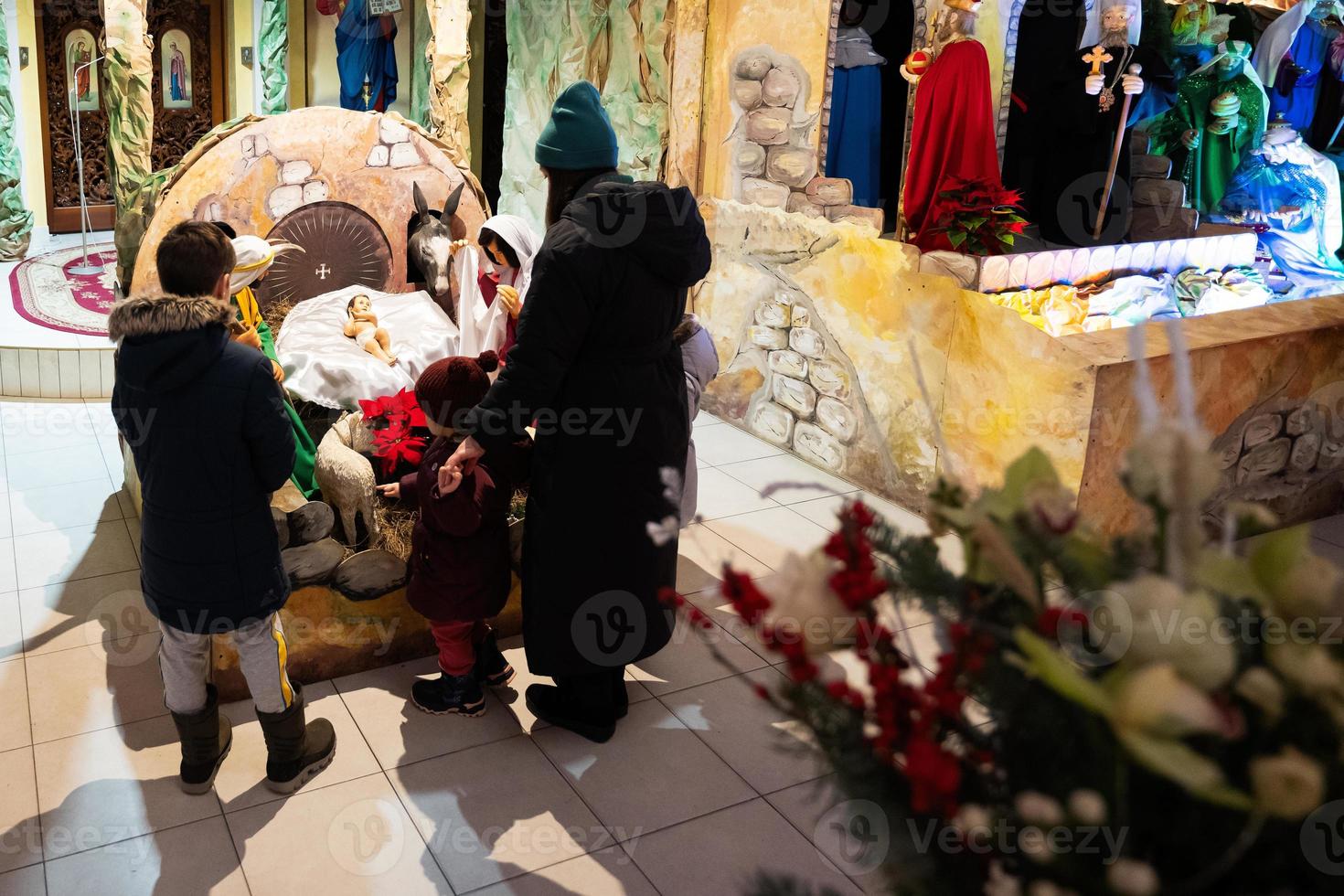 mère avec enfants visitent la crèche de noël à l'église. photo