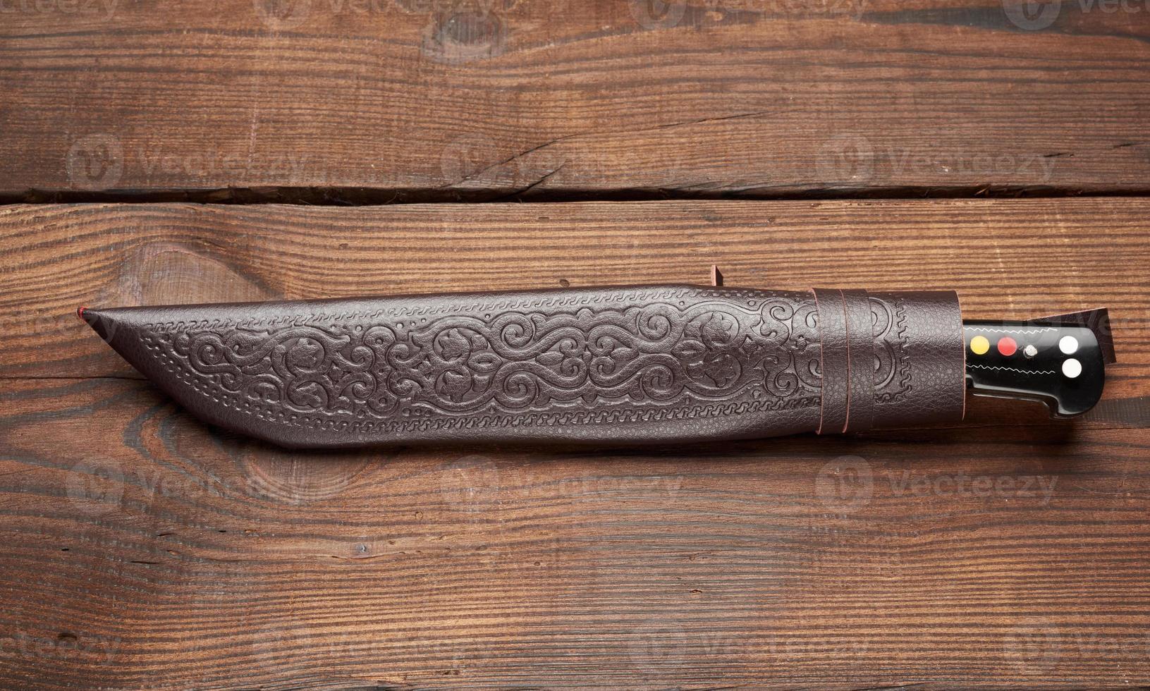 Couteau pointu universel traditionnel ouïghour ouzbek avec un manche noir sur un fond en bois marron photo