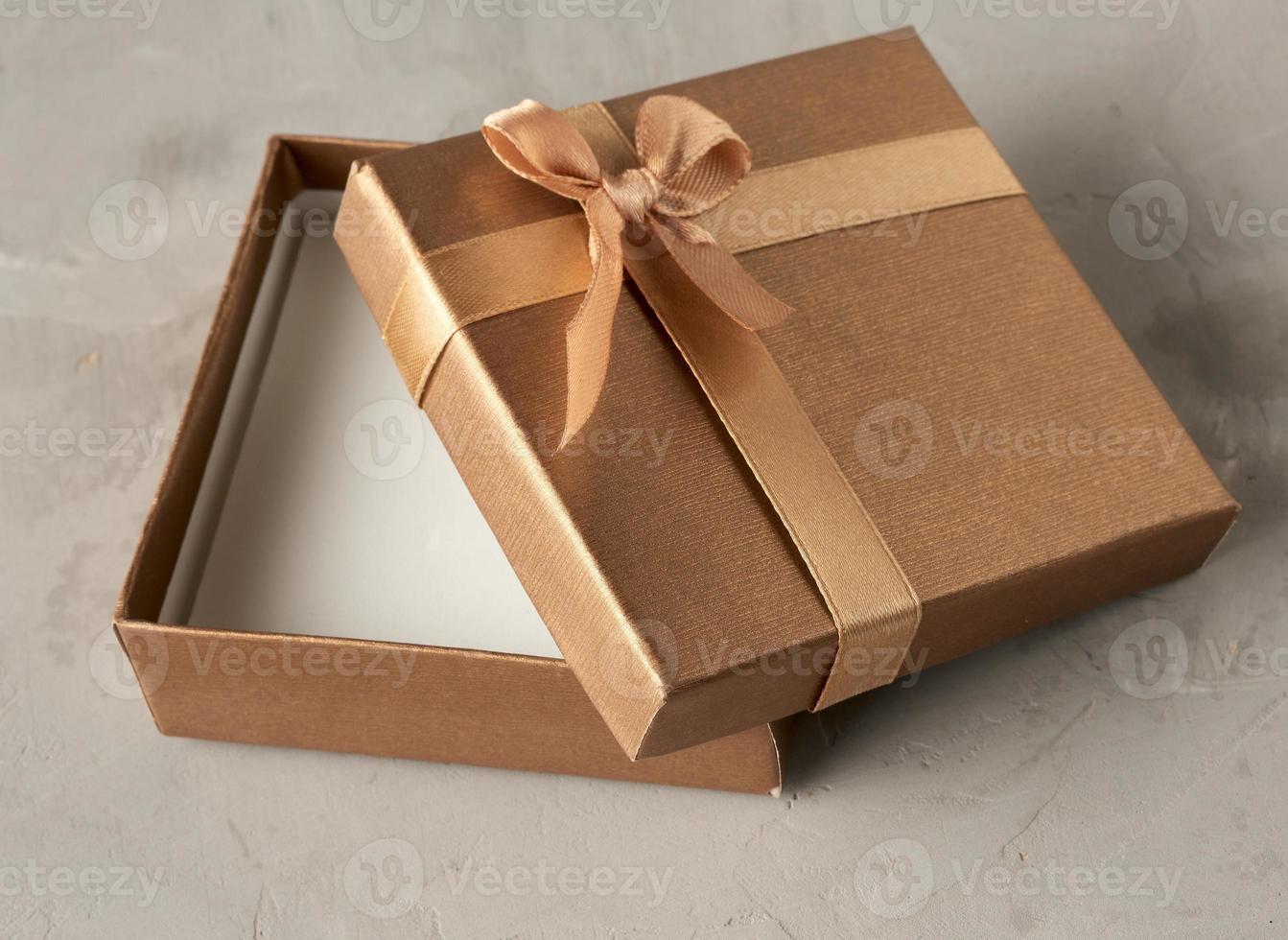 boîte cadeau carrée dorée ouverte sur fond gris photo