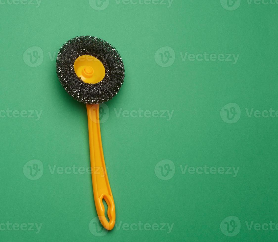 brosse en plastique jaune pour nettoyer la maison sur fond vert photo