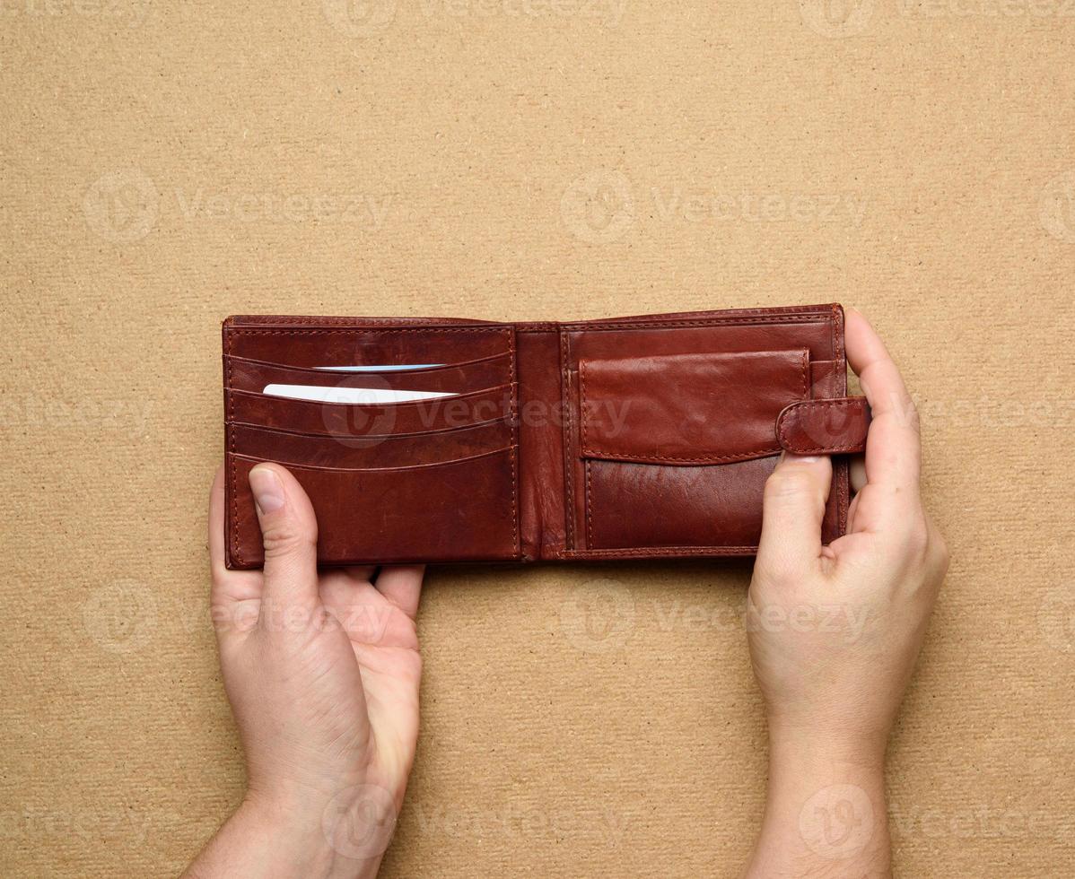 deux mains féminines tiennent un portefeuille ouvert en cuir marron pour de l'argent photo