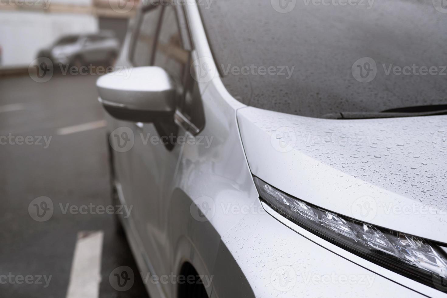 goutte de bruine de pluie sur le pare-brise en verre le soir. arrêter la rue de la voiture sous la pluie battante en ville. Veuillez conduire la voiture avec prudence, route glissante. mise au point douce. photo