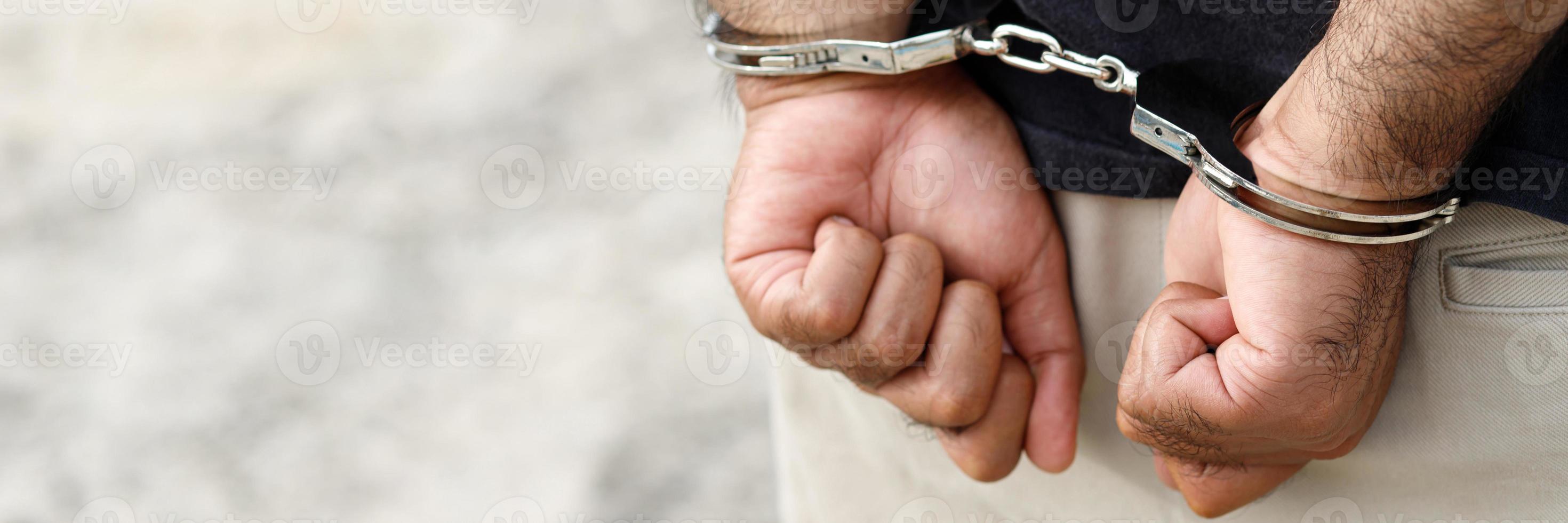 Homme prisonnier criminel debout menotté avec les mains derrière le dos photo
