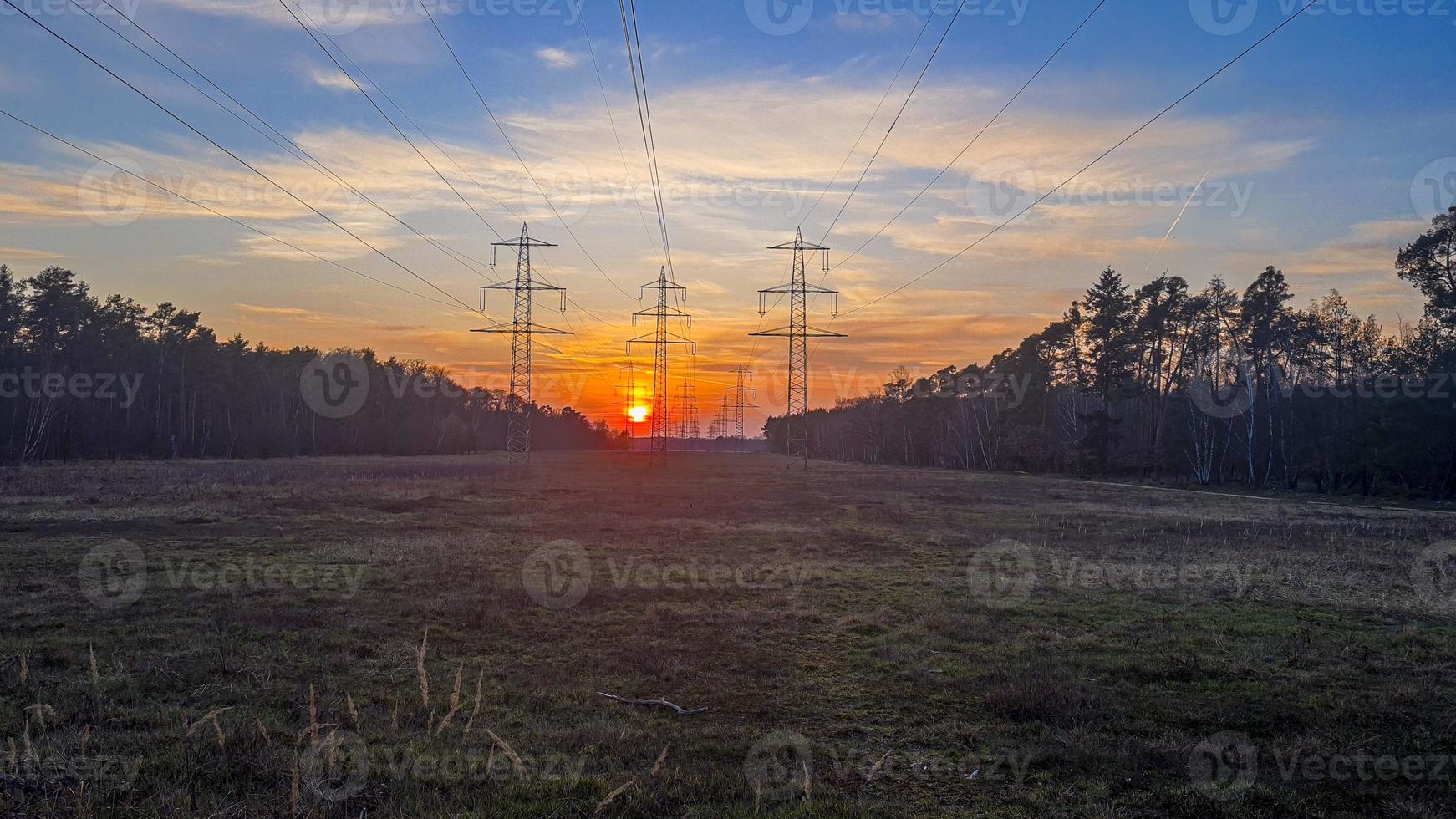 Poteaux électriques rétroéclairés photographiés au coucher du soleil en zone rurale photo