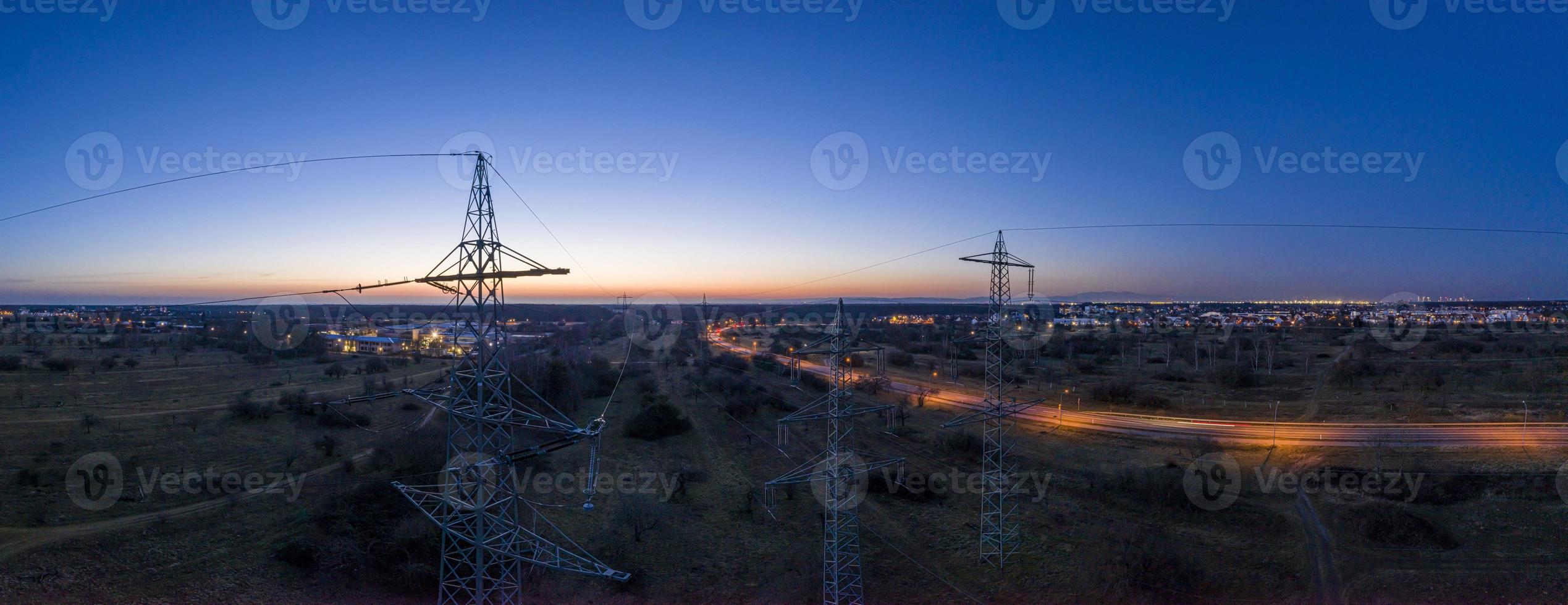 image panoramique des pylônes électriques contre le spectaculaire coucher de soleil rouge au crépuscule avec un ciel sans nuages photo