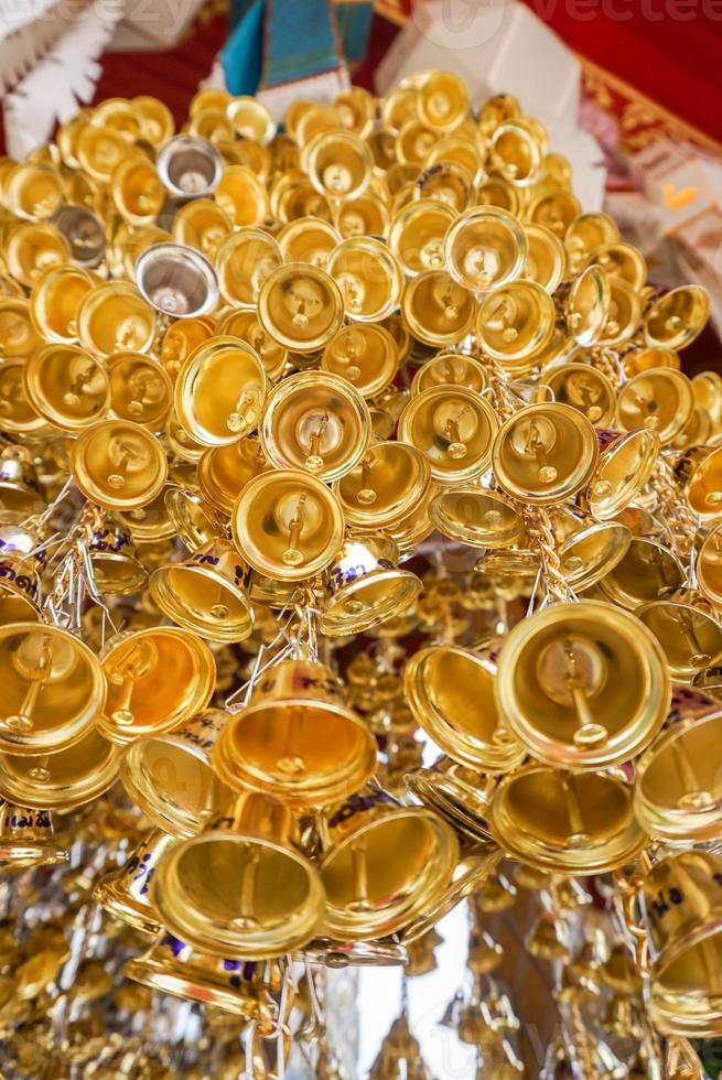 Regardez la vue de nombreuses petites cloches dorées accrochées dans un groupe dans un temple thaïlandais. photo