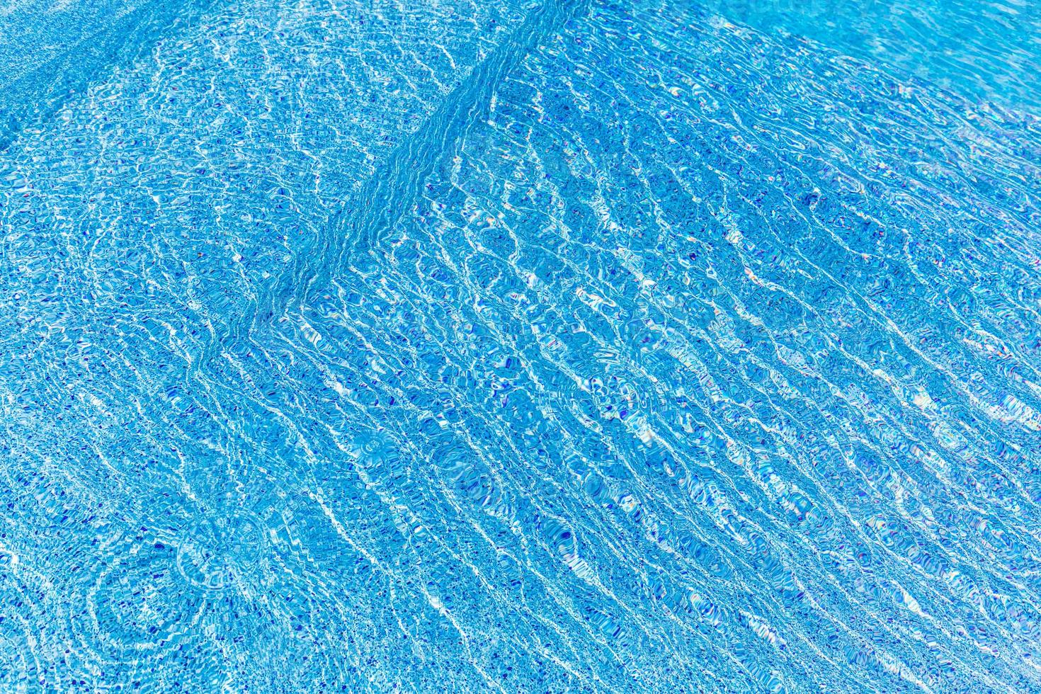 une belle eau de piscine avec un soleil relaxant scintille à la surface. vacances d'été ou concept de vacances, texture de piscine photo