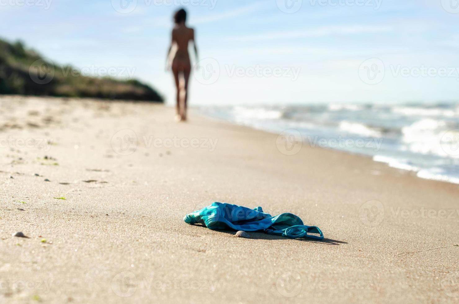 maillot de bain dans le sable sur la plage et figure féminine nue photo