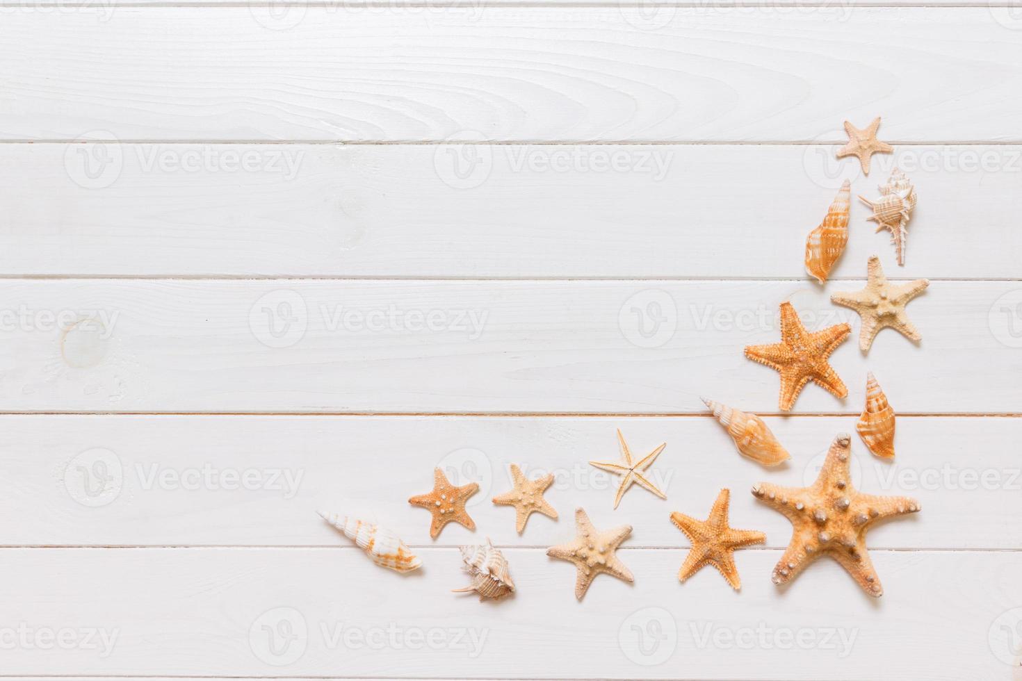 vue de dessus d'étoiles de mer et de nombreux coquillages sur la vue de dessus de fond de texture bois blanc. copiez l'arrière-plan de l'espace, concept d'été photo