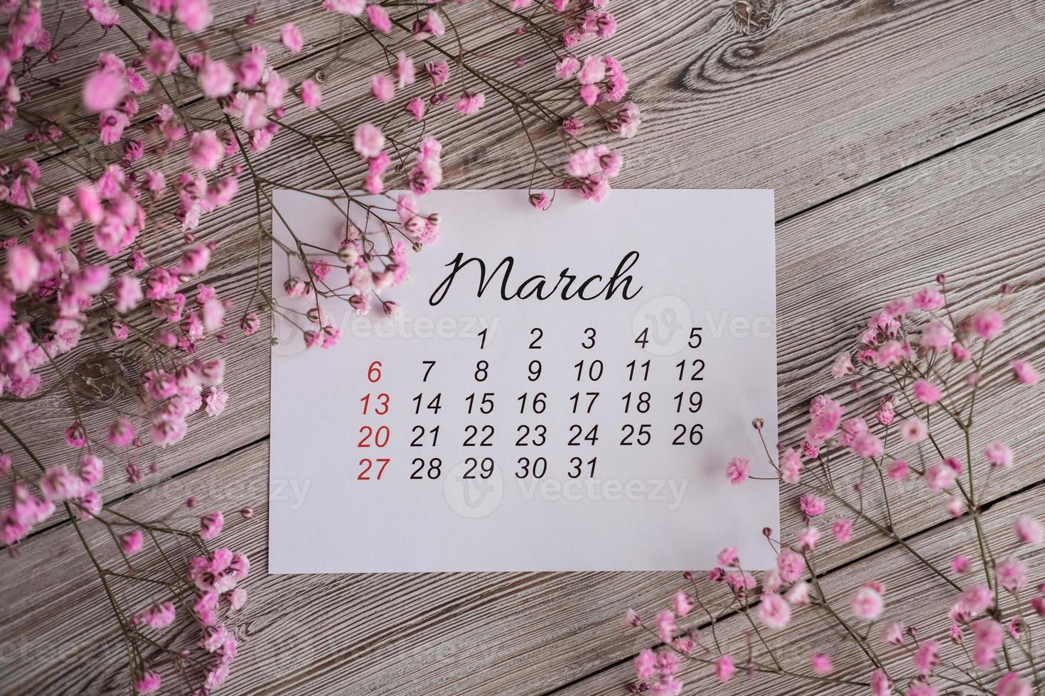 calendrier de mars 2022 et fleurs roses sur fond de bois. calendrier à plat photo