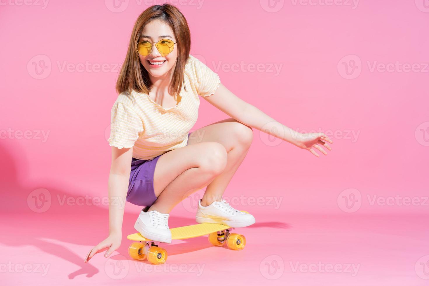 photo d'une adolescente asiatique avec planche à roulettes sur fond rose