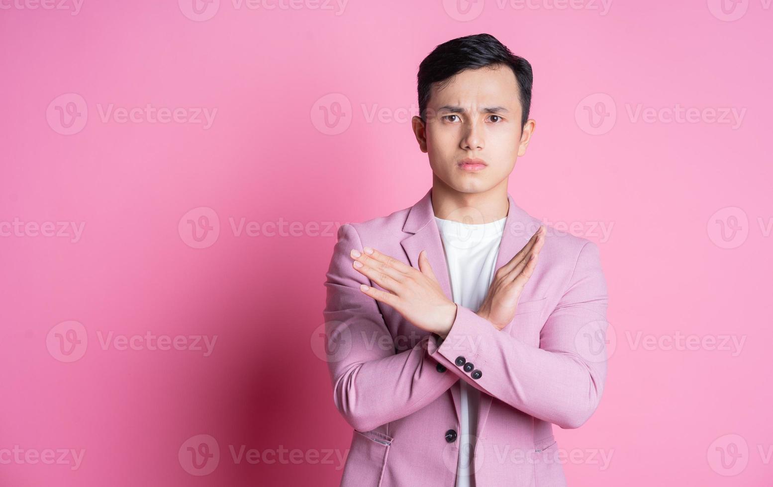 portrait de jeune homme asiatique portant un costume rose posant sur fond photo