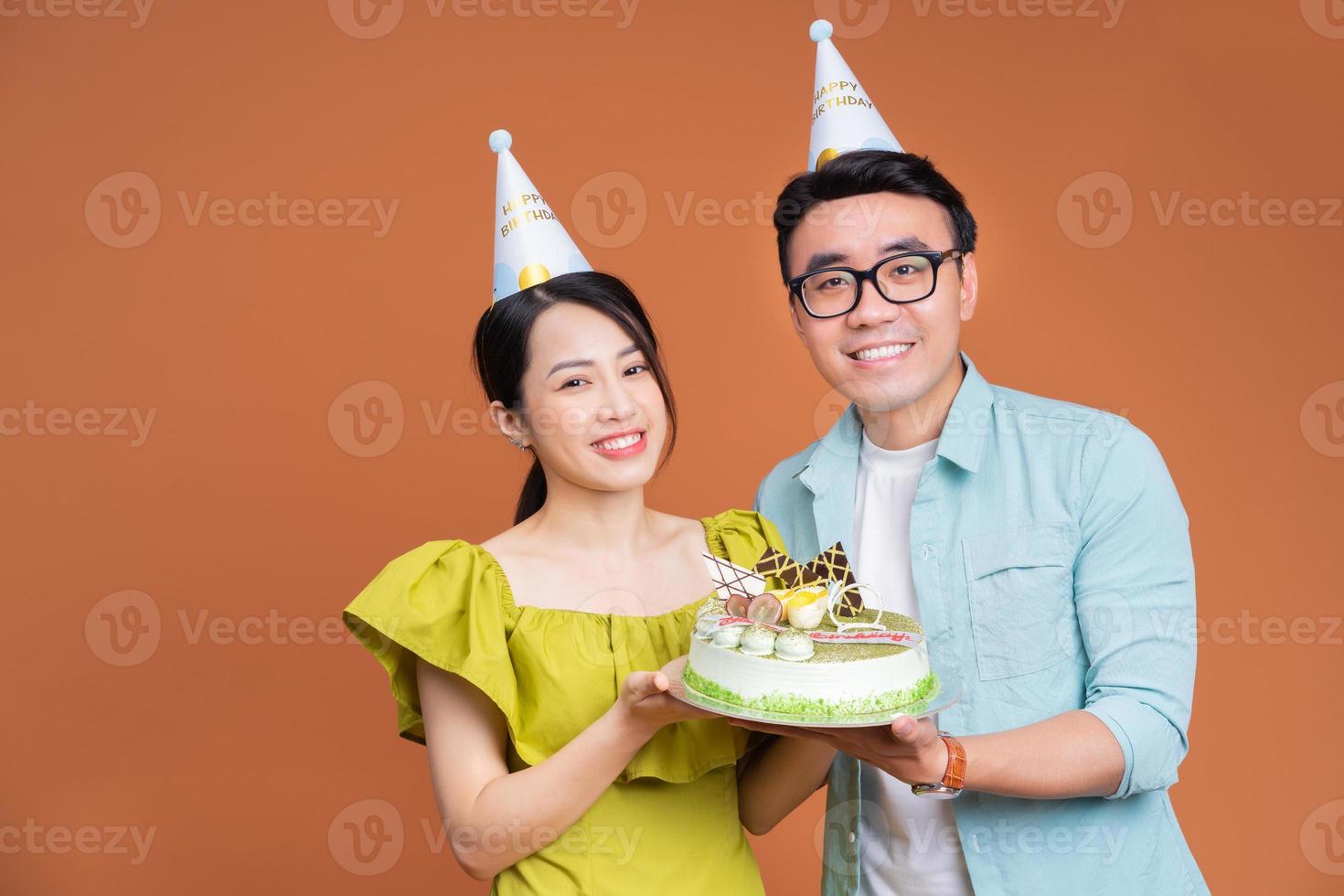 jeune couple asiatique tenant un gâteau d'anniversaire sur fond photo