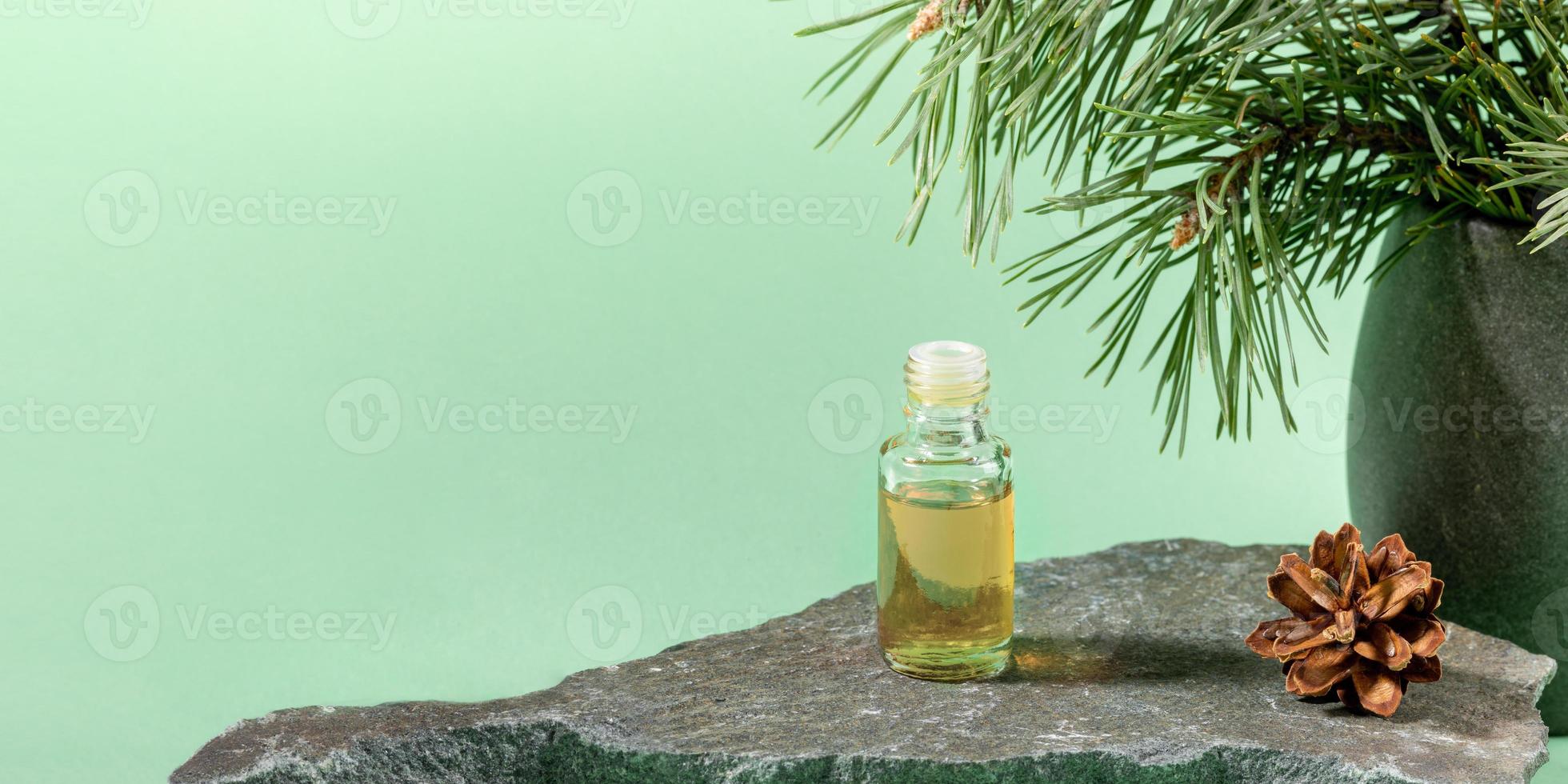 bouteille en verre d'huile essentielle de pin sur pierre grise sur vert menthe. bannière publicitaire. photo