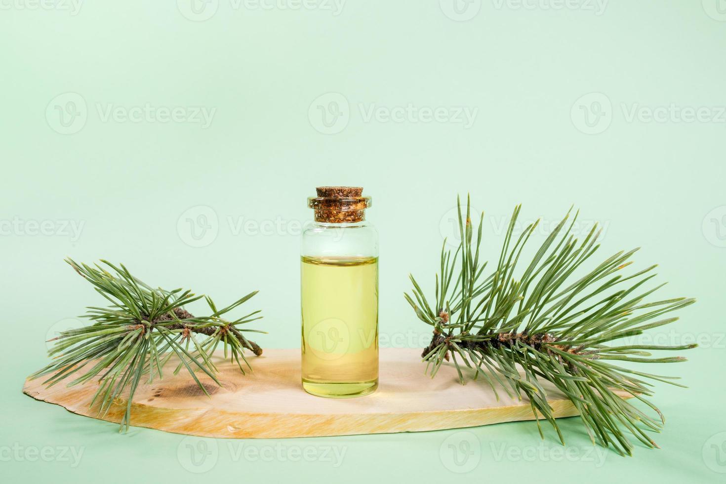 une petite bouteille en verre avec de l'huile essentielle de pin sur une scie à bois coupée sur du vert menthe. photo
