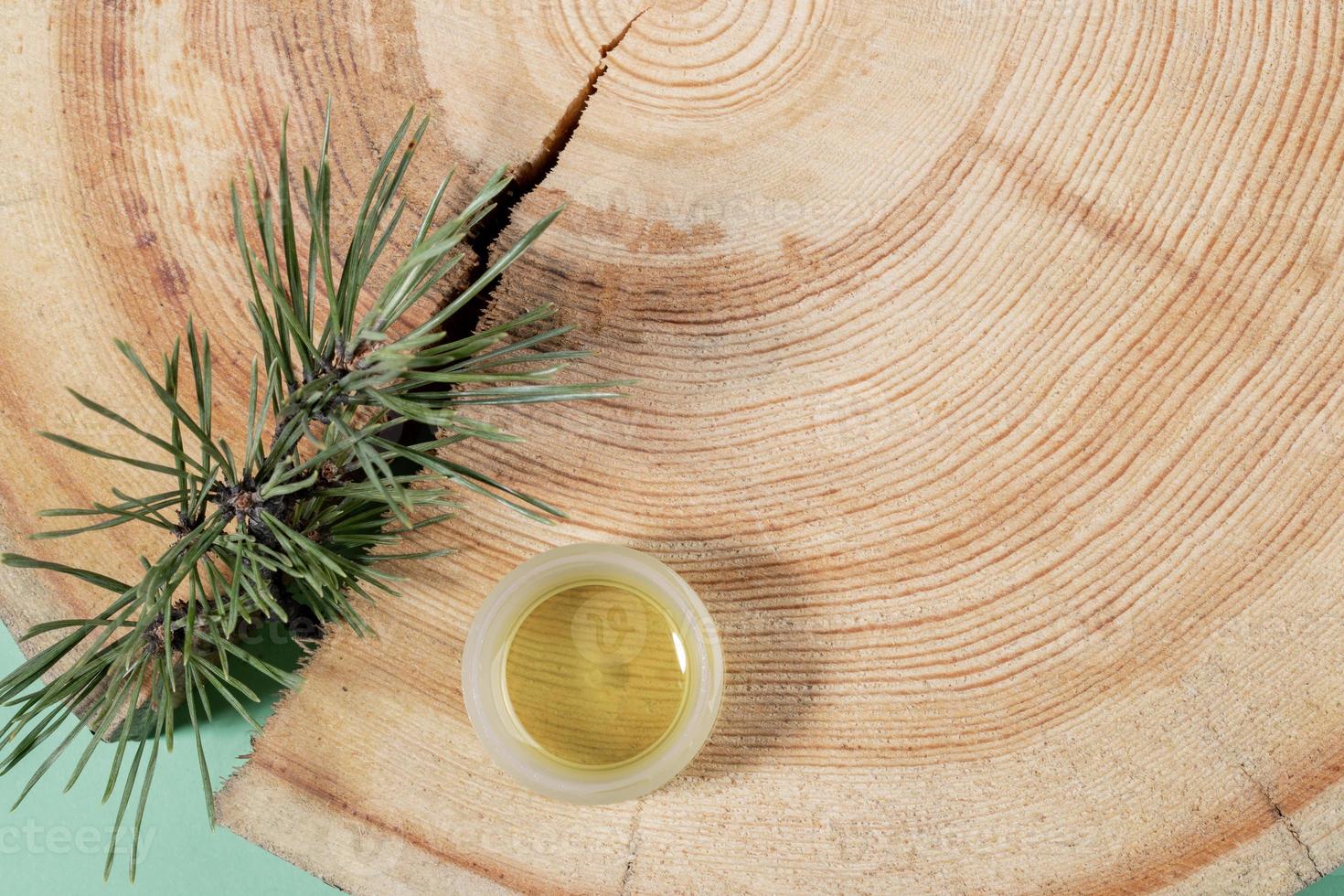 concept d'aromathérapie naturelle et de spa - petit pot en verre d'huile essentielle de pin, branche, scie en bois coupée avec anneaux annuels. photo