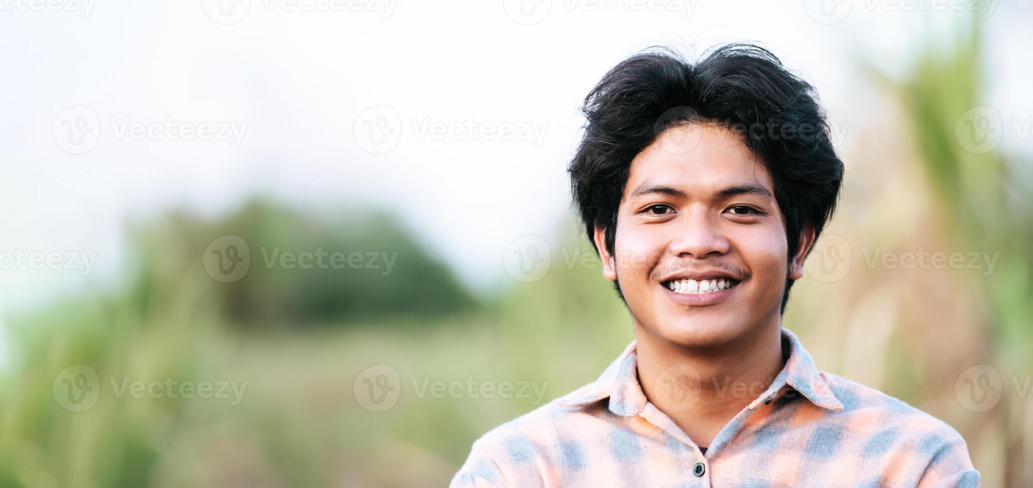 portrait asiatique jeune homme sourire avec plaisir dans le champ de maïs photo